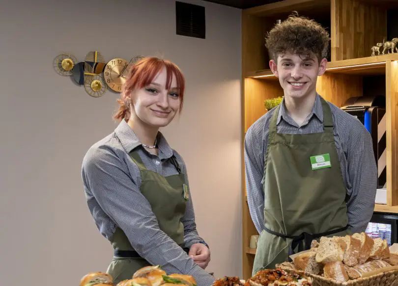 A couple of smiling staff members serving food