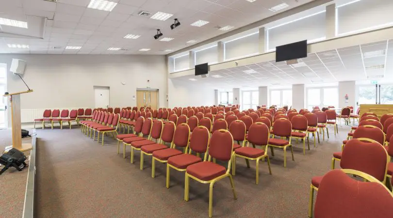 Large conference hall with stage and rows of chairs