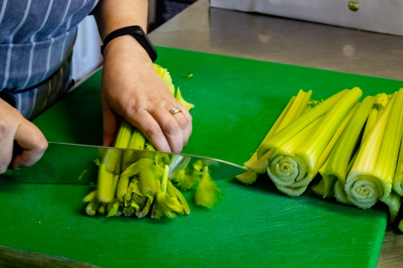 An image of Nadia slicing celery on a chopping board