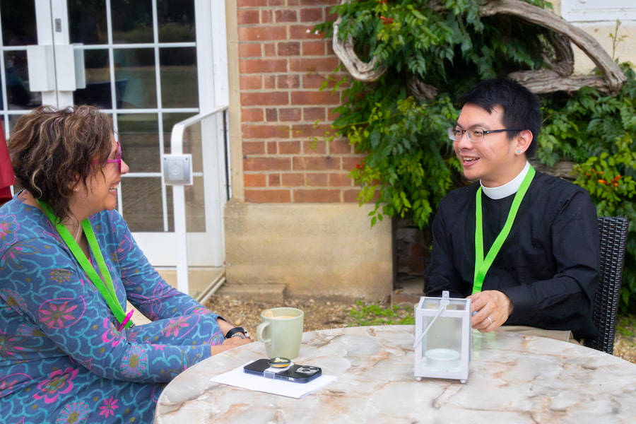 A man and woman talking and smiling over a coffee in an outdoor seating area