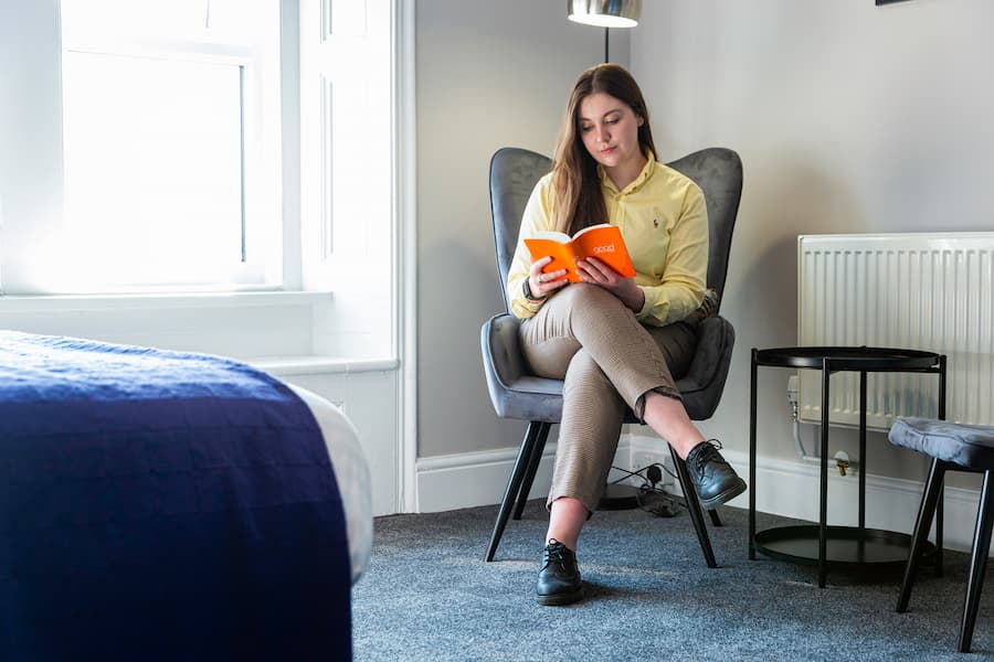 A woman sitting in an armchair reading her Bible.