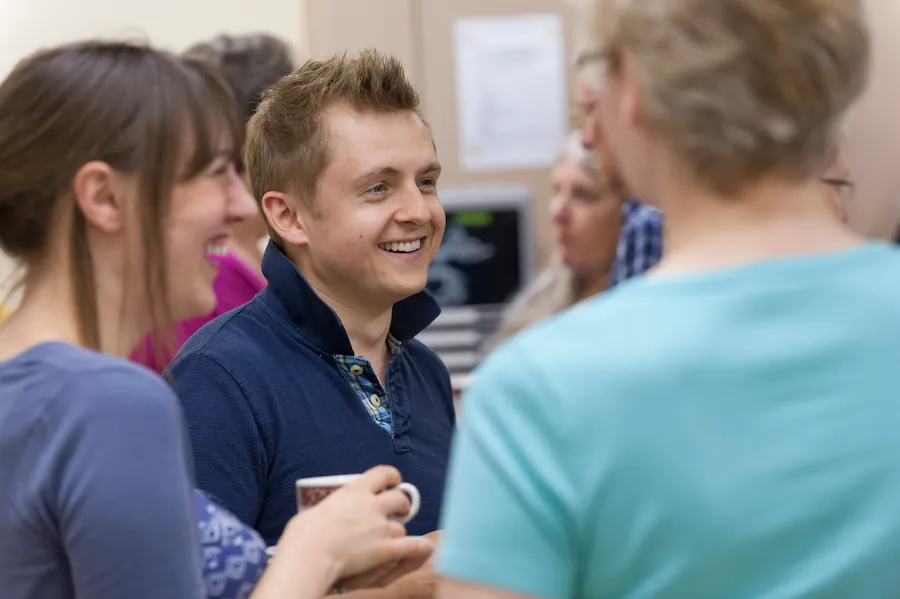 A young man spending laughing while fellowshipping with other church leaders during a conference at High Leigh