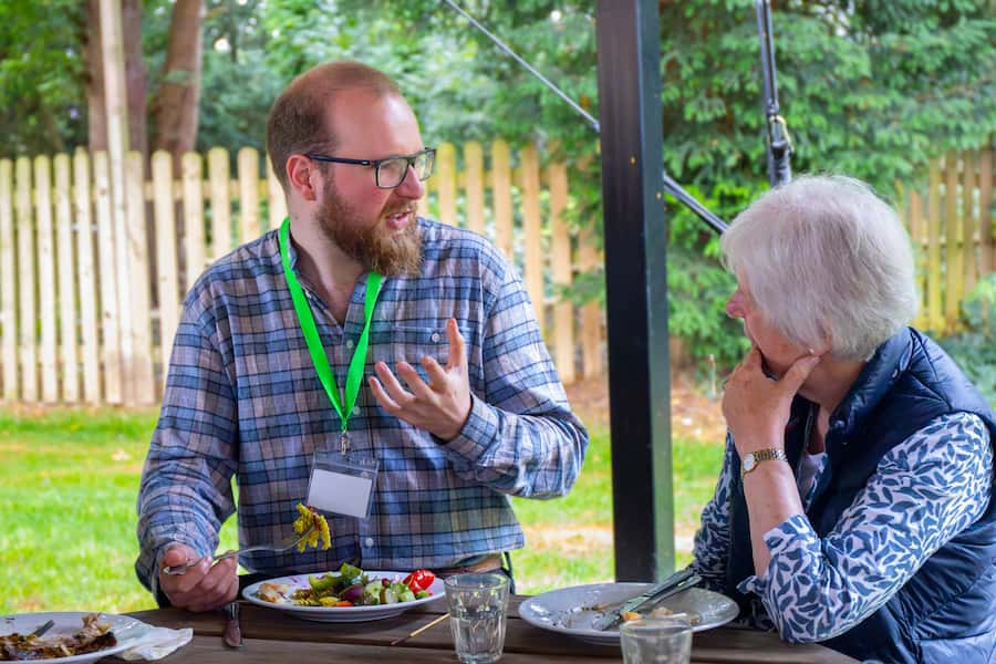 A young man talking with an elderly woman at the table over lunch.