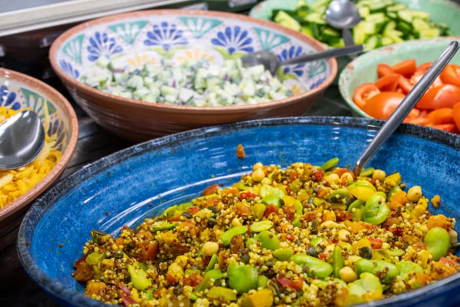 Multiple bowls of different colourful salads including quinoa and others.