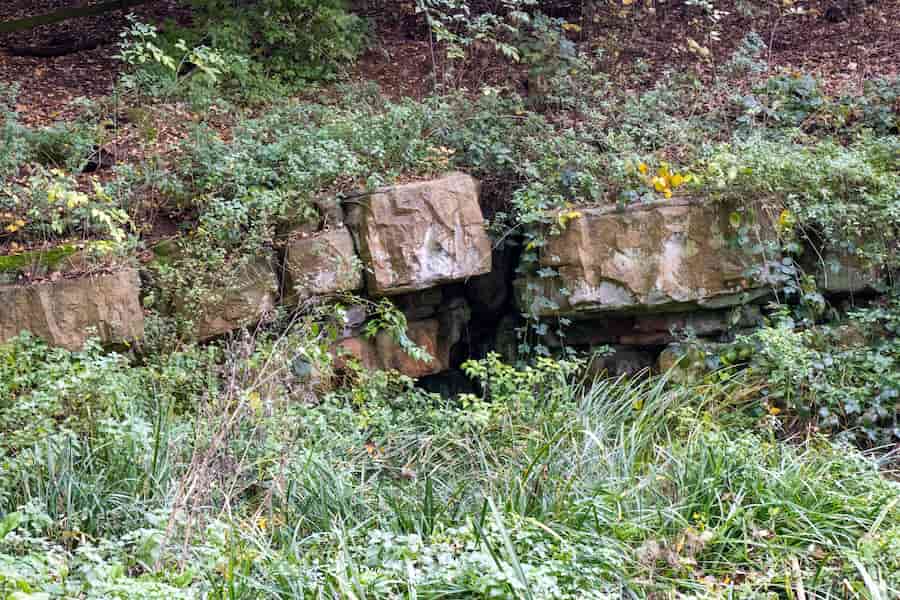 The Pulhamite rockery and cave surrounded in greenery and down by the lake.