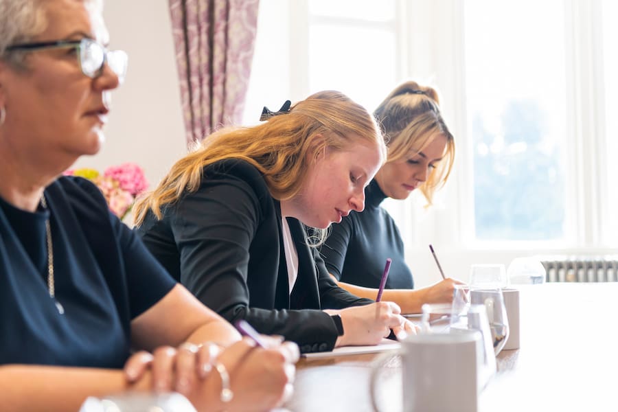 A woman writing down her aims and goals for the year ahead on a boardroom table.