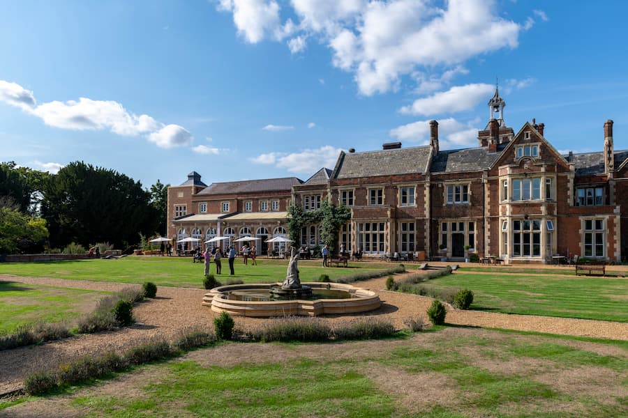 A beautiful photo of High Leigh, looking across the grounds over the fountain at the outdoor seating just outside the coffee area at High Leigh, displaying its grandeur.