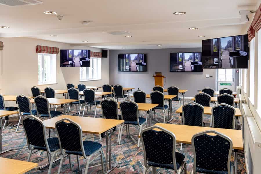 An image of walnut room set in classroom style with the tv screens on.