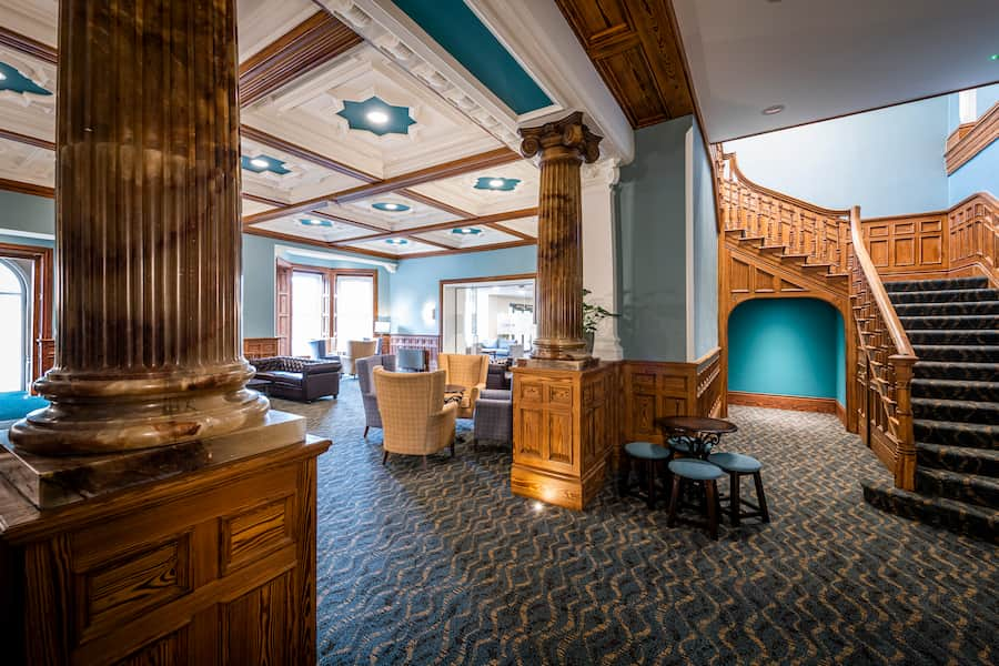 An image of The Hayes' Brown Lounge, featuring its magnificent marble pillars and winding staircase. 