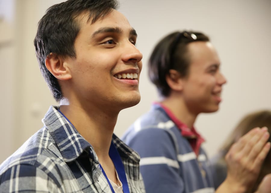 A young man smiling during a conference meeting.