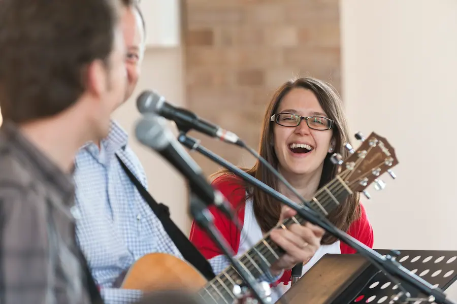 A young church leader laughing at a conference with other musicians all having a good time together.