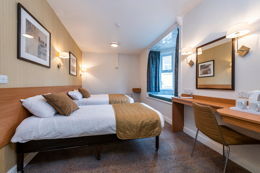 A twin bedroom with a bright bay window and seating area.