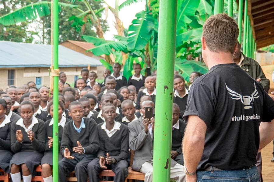 A member of Paddy & Scott's team standing before a school of children in Kenya.