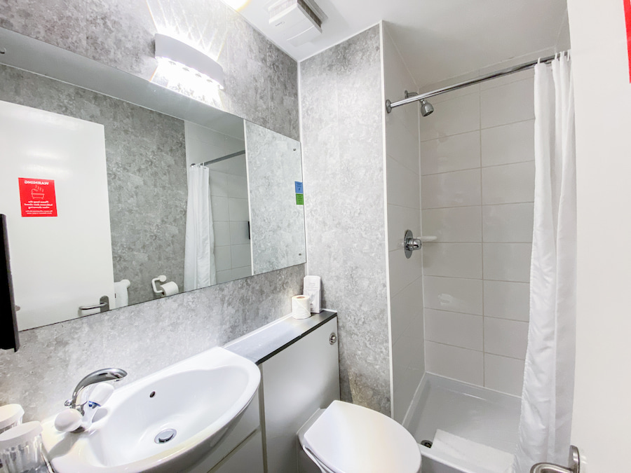 A bathroom with grey vinyl walls and bright LED lighting.