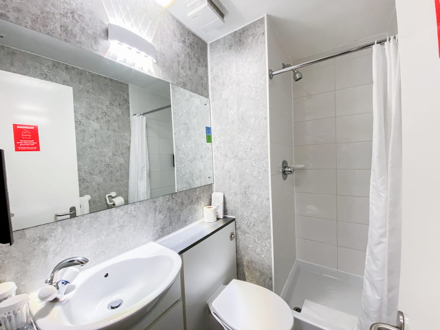 A Cherry bathroom after renovations with improved lighting and grey modern grey patterned walls