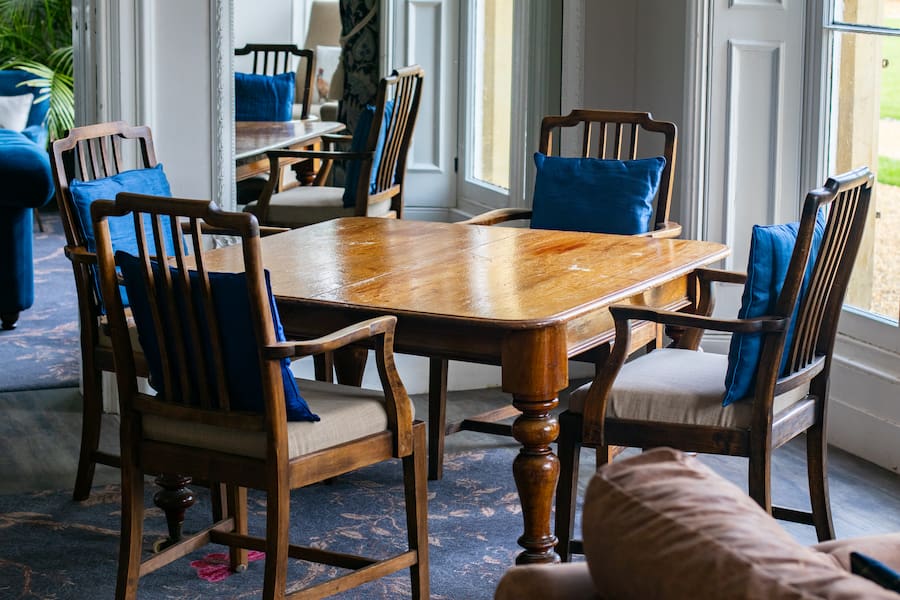 The original table and chairs from almost 100 years ago with blue cushions on in the Woodlands Lounge.