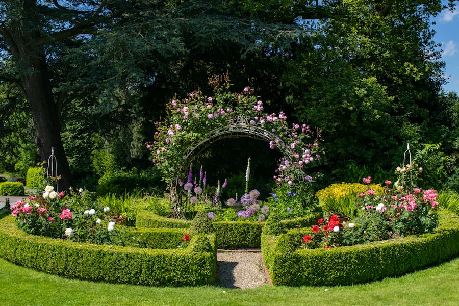 A section of The Hayes' garden with a rose arch and colourful flowers