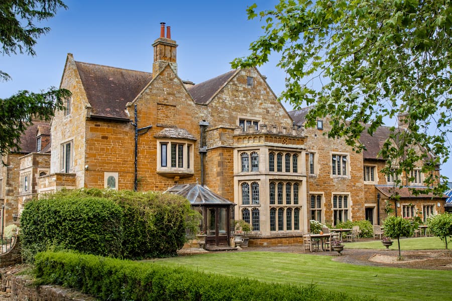 Highgate House conference centre with part of its gardens with a large tree on the right side.