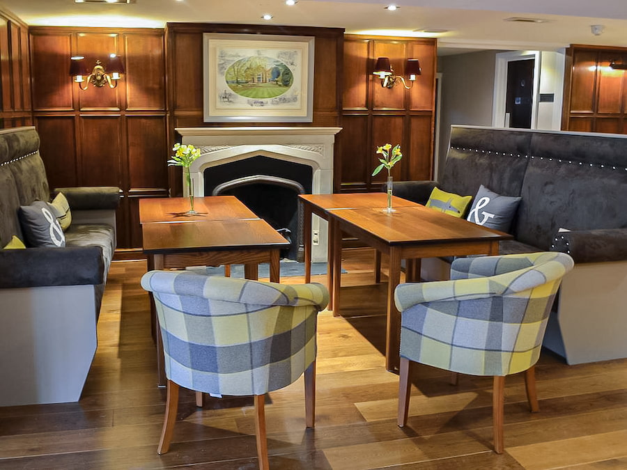 The lounge area at Highgate House with comfortable seating and an open fireplace.