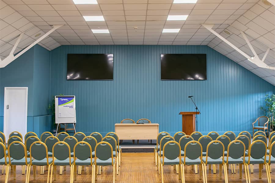 The Main Conference Hall with a theatre style set up and the 2 large screen hung up on the blue back wall.