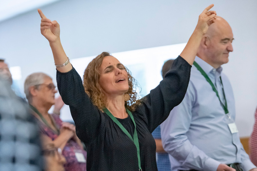 A woman worshipping at one of our conference centres with a green lanyard on.