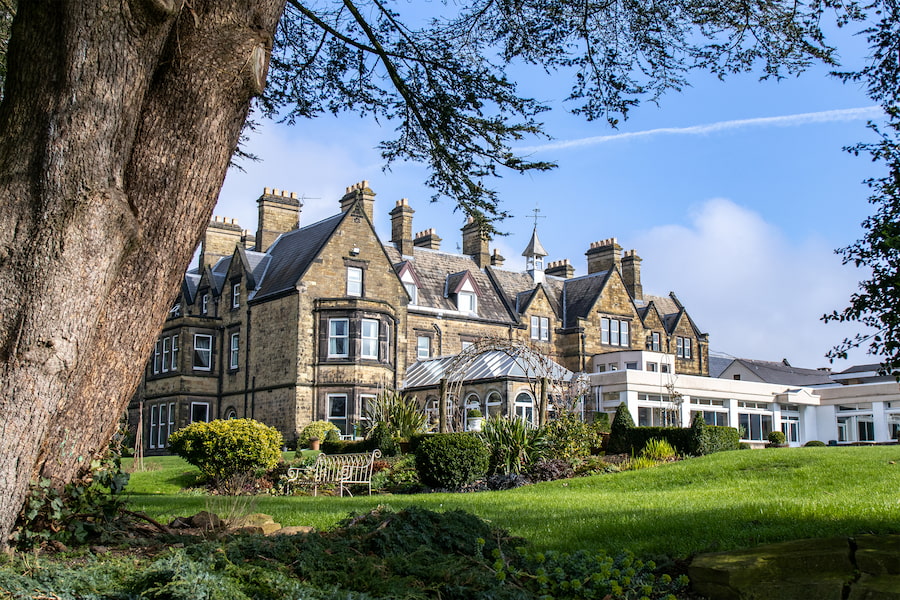 The Hayes conference centre showing its gardens, a rose arch, and very large old tree.