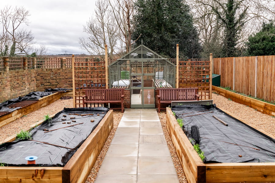 The Market Garden at High Leigh showing a pathway leading between to garden beds up to a Victorian-style greenhouse