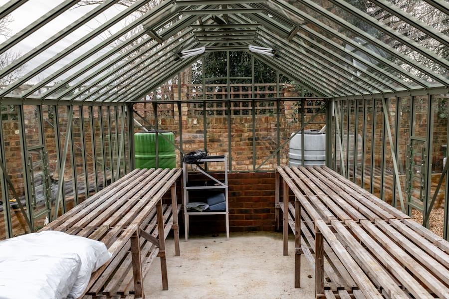 The interior of the greenhouse with empty shelving.