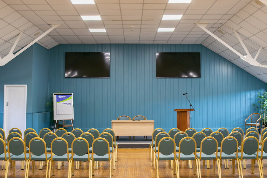 Main Conference Hall with its 2 large 4k screens at the front.